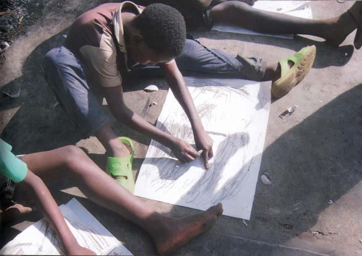 'Jongens actief met tekenoefening van uit beweging met beide handen met houtskool'.'Jongens actief met tekenoefening van uit beweging met beide handen, getekend met houtskool'. Nairobi - Kenya.